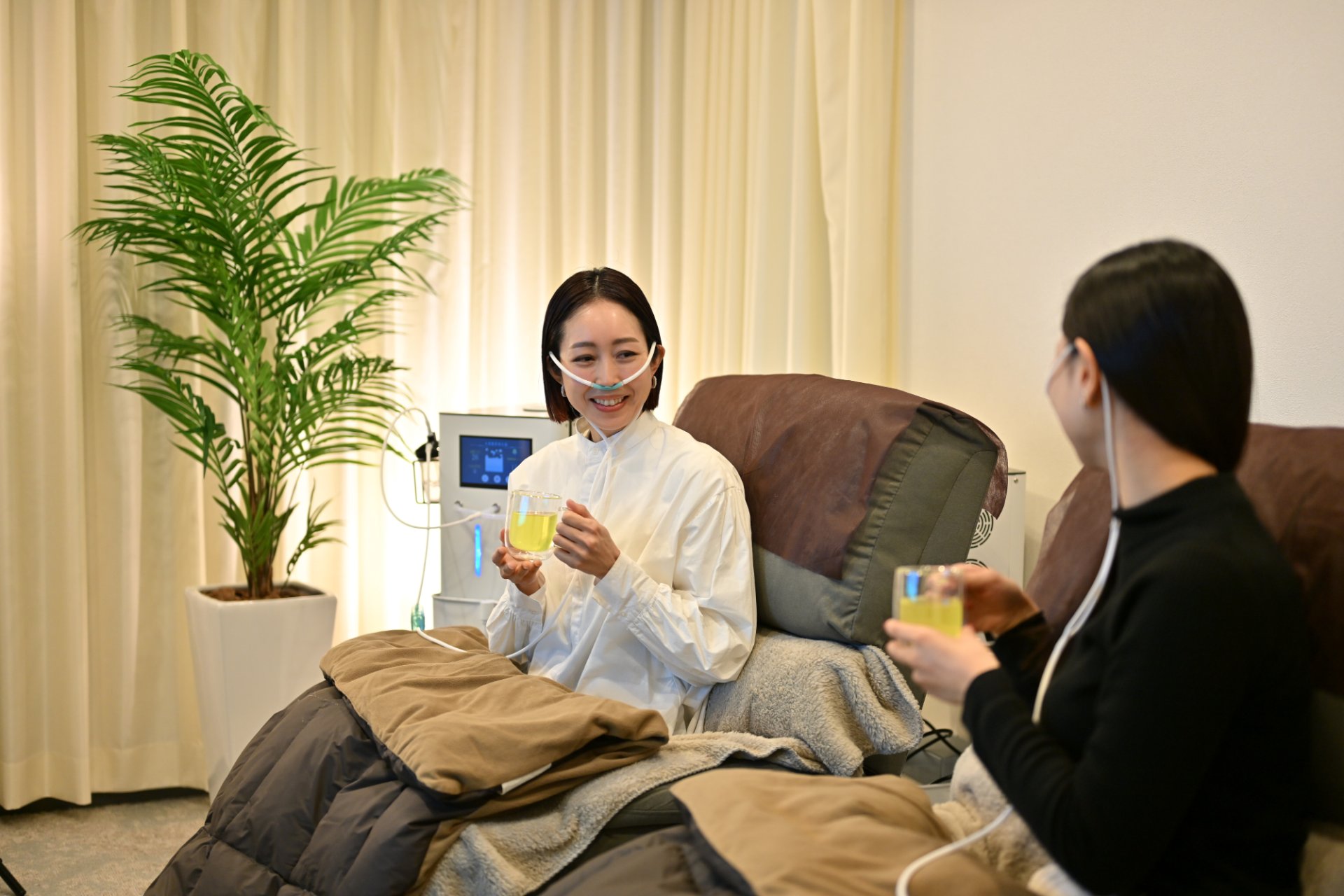 水素・酸素吸入を受けながらお茶を飲んでくつろぐ女性たち